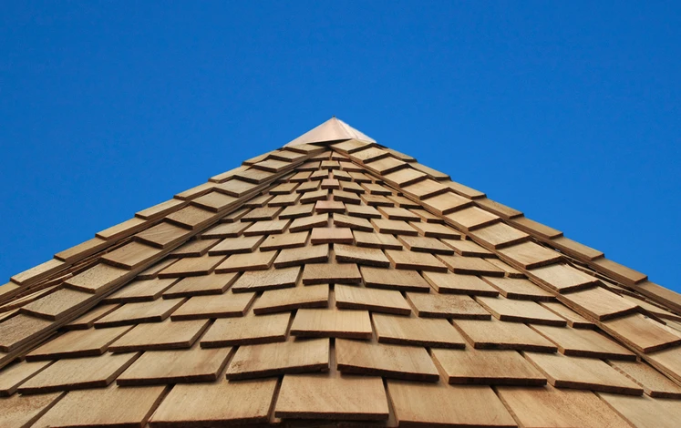 Extérieur, vue en contre-plongée d'une toiture en construction sous ciel bleu azur