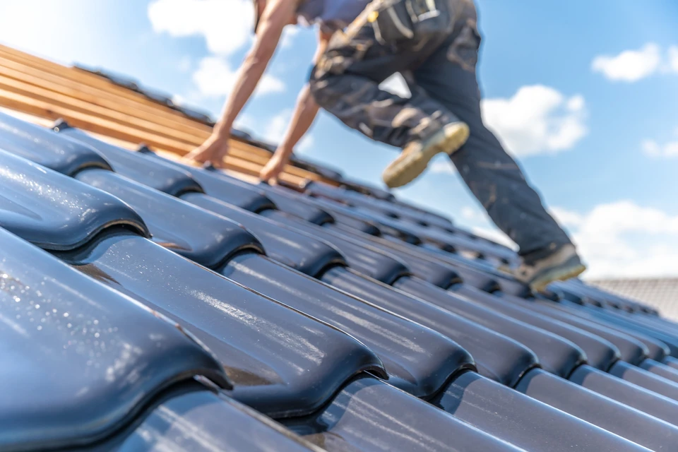 Ouvrier en tenue de travail sur toiture résidentielle effectuant des travaux de couverture