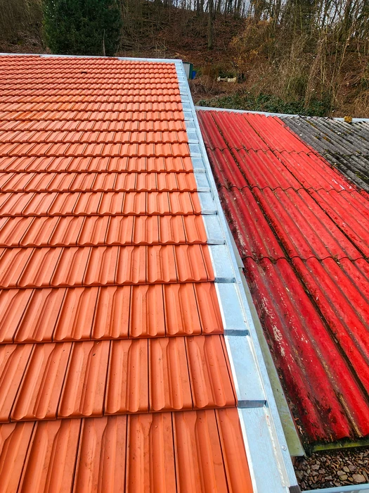 Vue depuis un toit en cours de rénovation, tuiles en terre cuite neuves de type romane, faîtage apparent au premier plan
