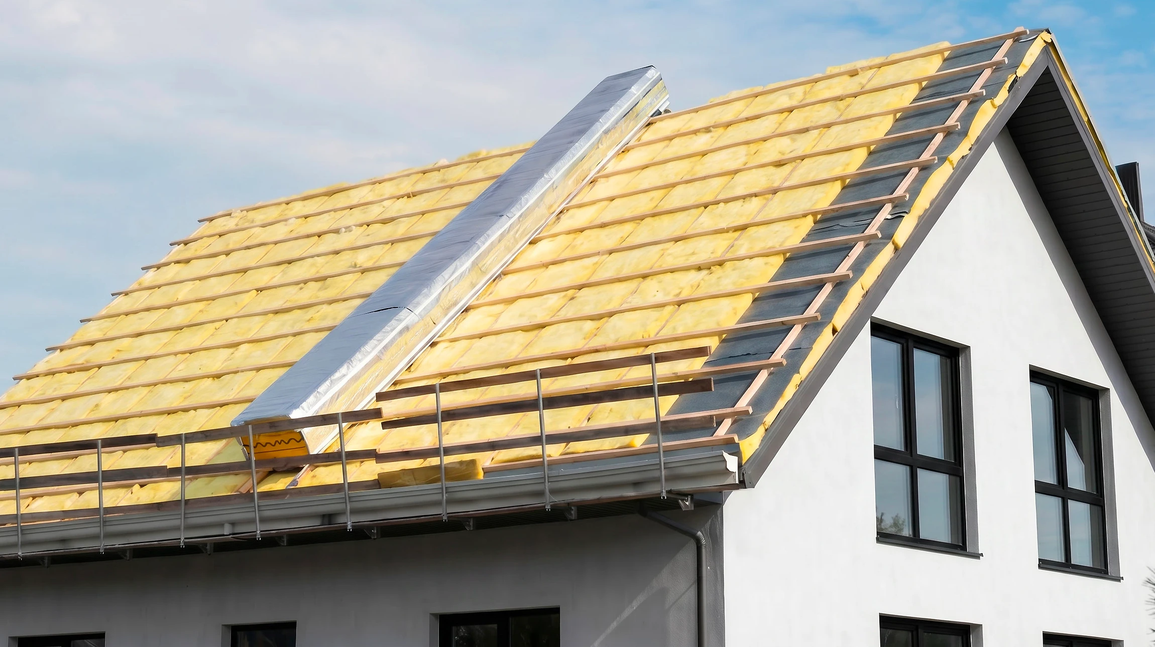 Ouvrier en équipement de protection travaillant sur isolation thermique d'une toiture en pente